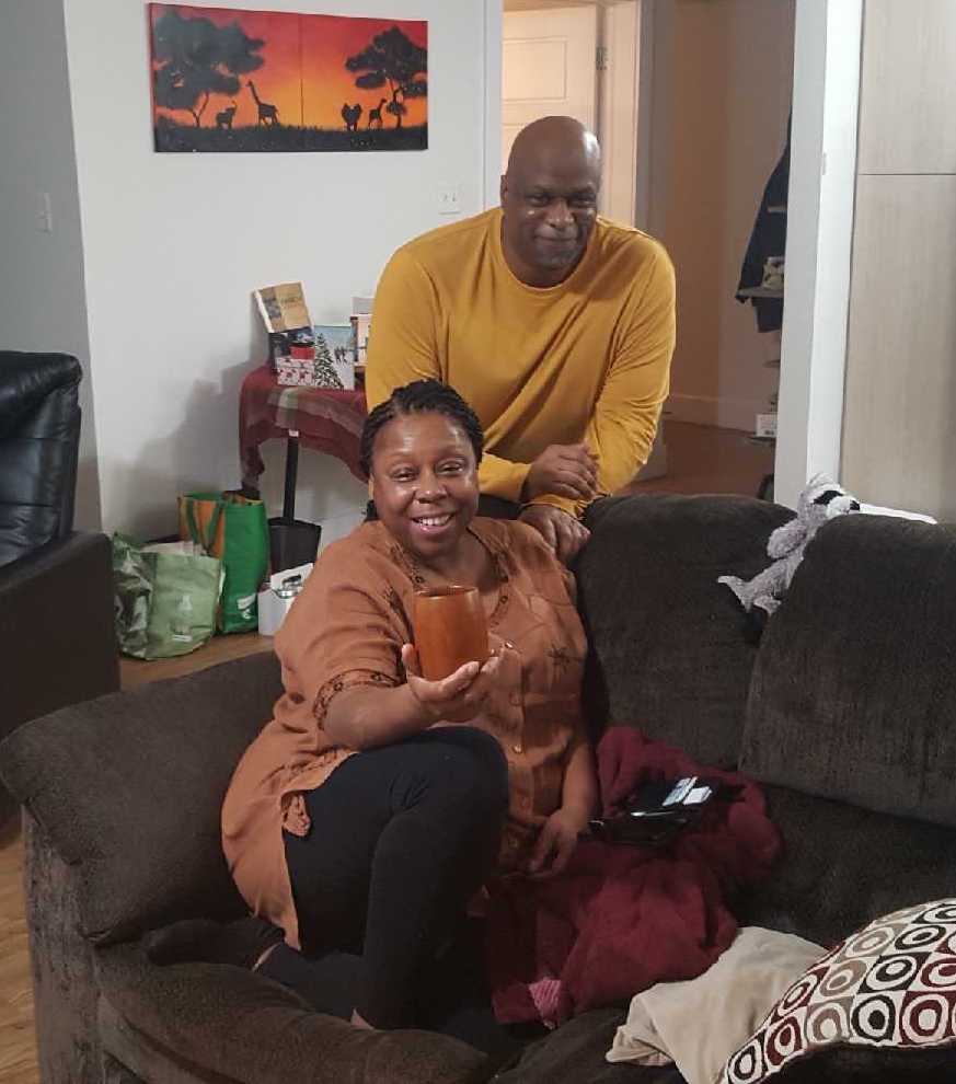 Black couple in their living room smile for the camera