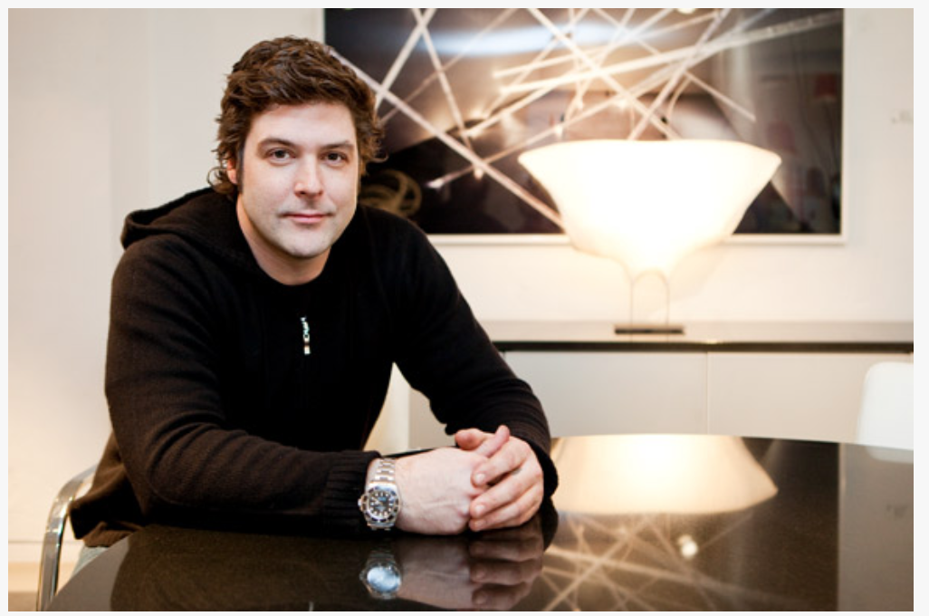 一个人双手交叉坐在桌子旁。