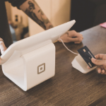 当顾客递出Visa卡时，一个人在使用小型借记卡机。