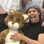 一位年轻的黑人妇女拿着一个大的毛绒玩具大笑