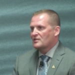 一个穿着西装的中年白人男子向大规模伤亡委员会讲话