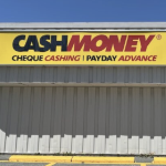 灰色的建筑物上有一个写着“现金”的黄色标志