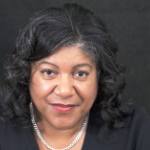 A smiling Black woman with wavy hair and a black top