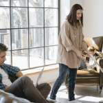 一个白人妇女在她的白人丈夫休息时用吸尘器吸尘