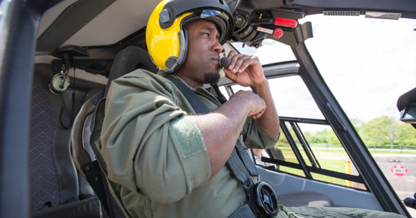 一个戴着黄色头盔的黑人坐在直升机驾驶舱里