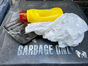 垃圾桶上放着一个塑料罐、泡沫塑料容器和塑料袋