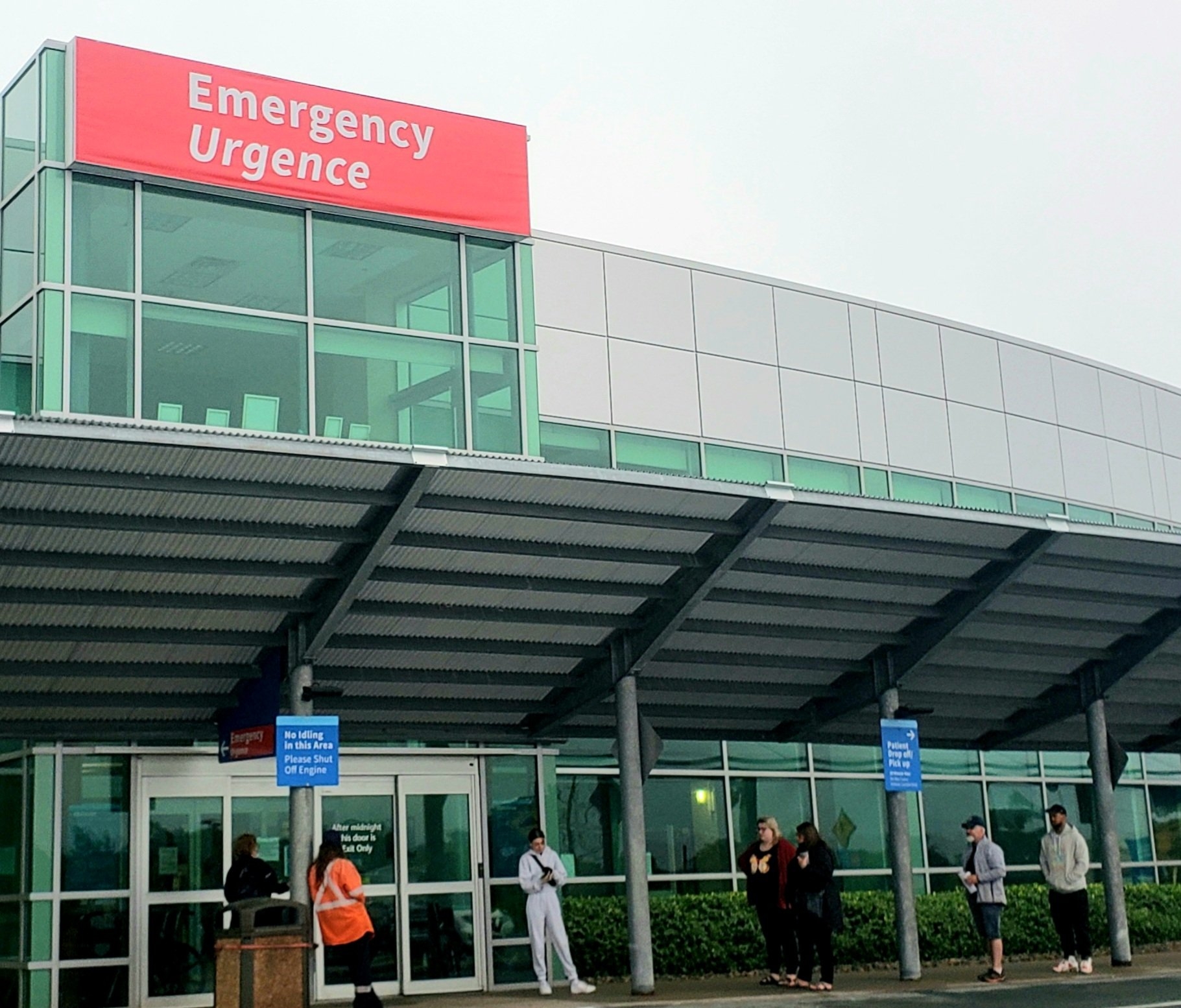 一群保持社交距离的人在科bequid急诊科门前排队，等待开门。