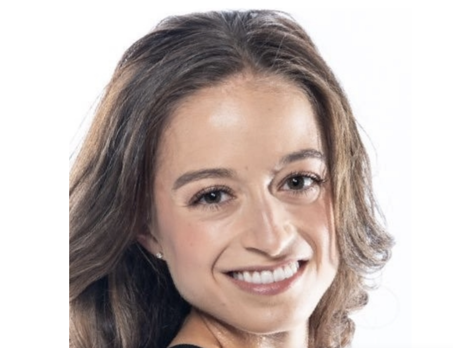 一个微笑的黑发女人，肩长头发望着她的肩膀，对着相机微笑。