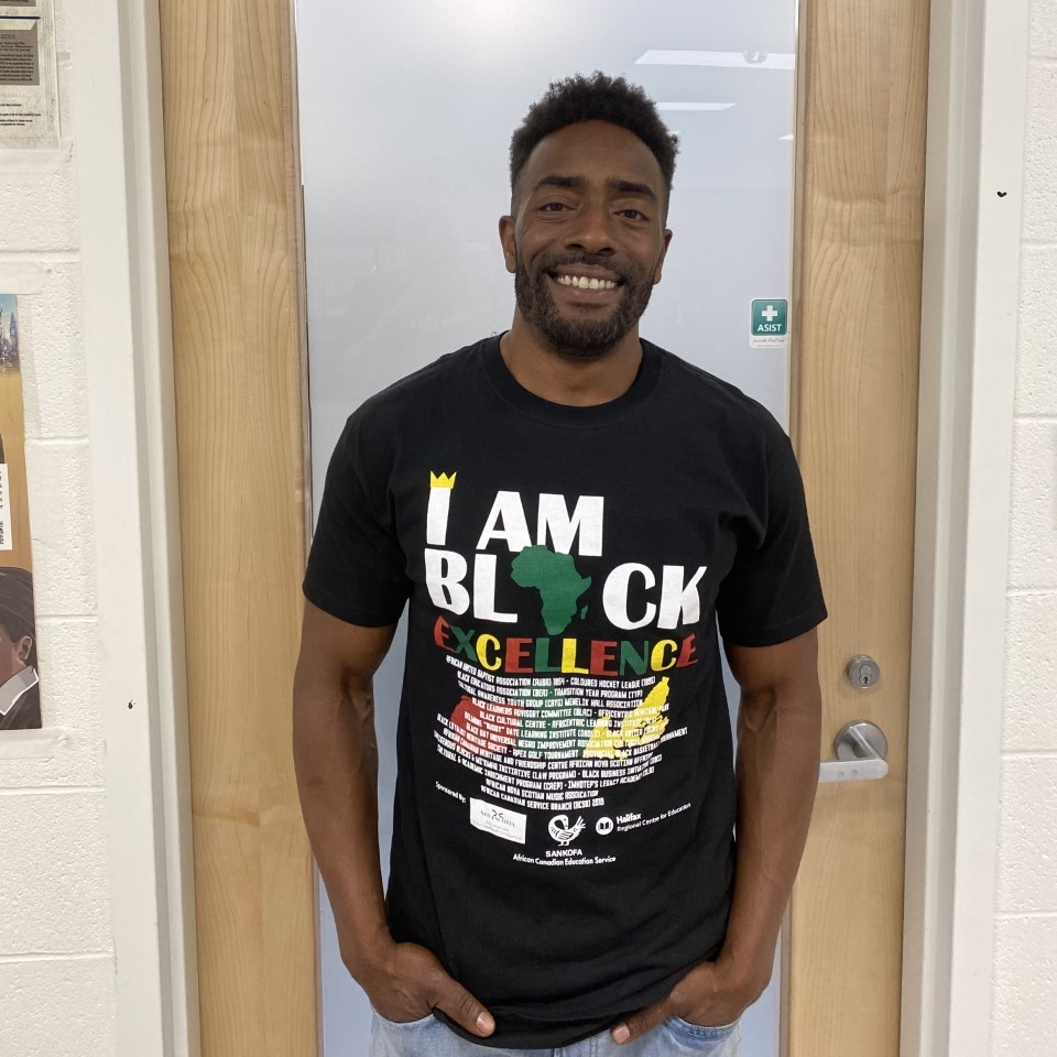 一名身穿“我是优秀黑人”t恤的黑人对着镜头微笑。