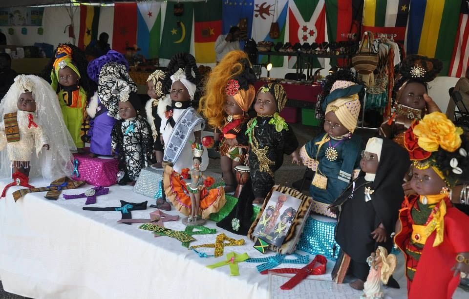 穿着各种非洲服装的非洲娃娃和其他商品陈列在桌子上。