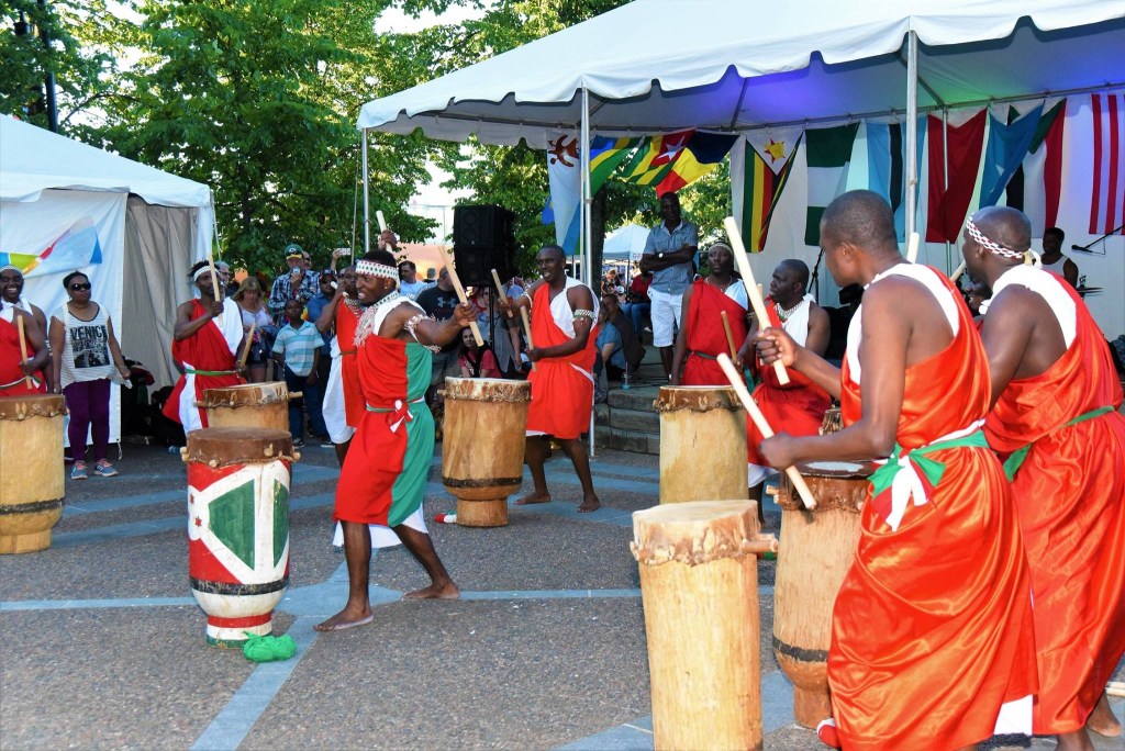 节日期间，身穿橙色非洲服装的非洲鼓手在街头表演。