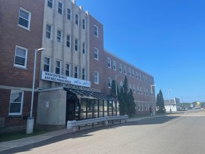 一座四层砖砌建筑，有一个玻璃前门。入口前面有一条车道。门的上方有一个牌子，上面写着正门。迪格比综合医院。