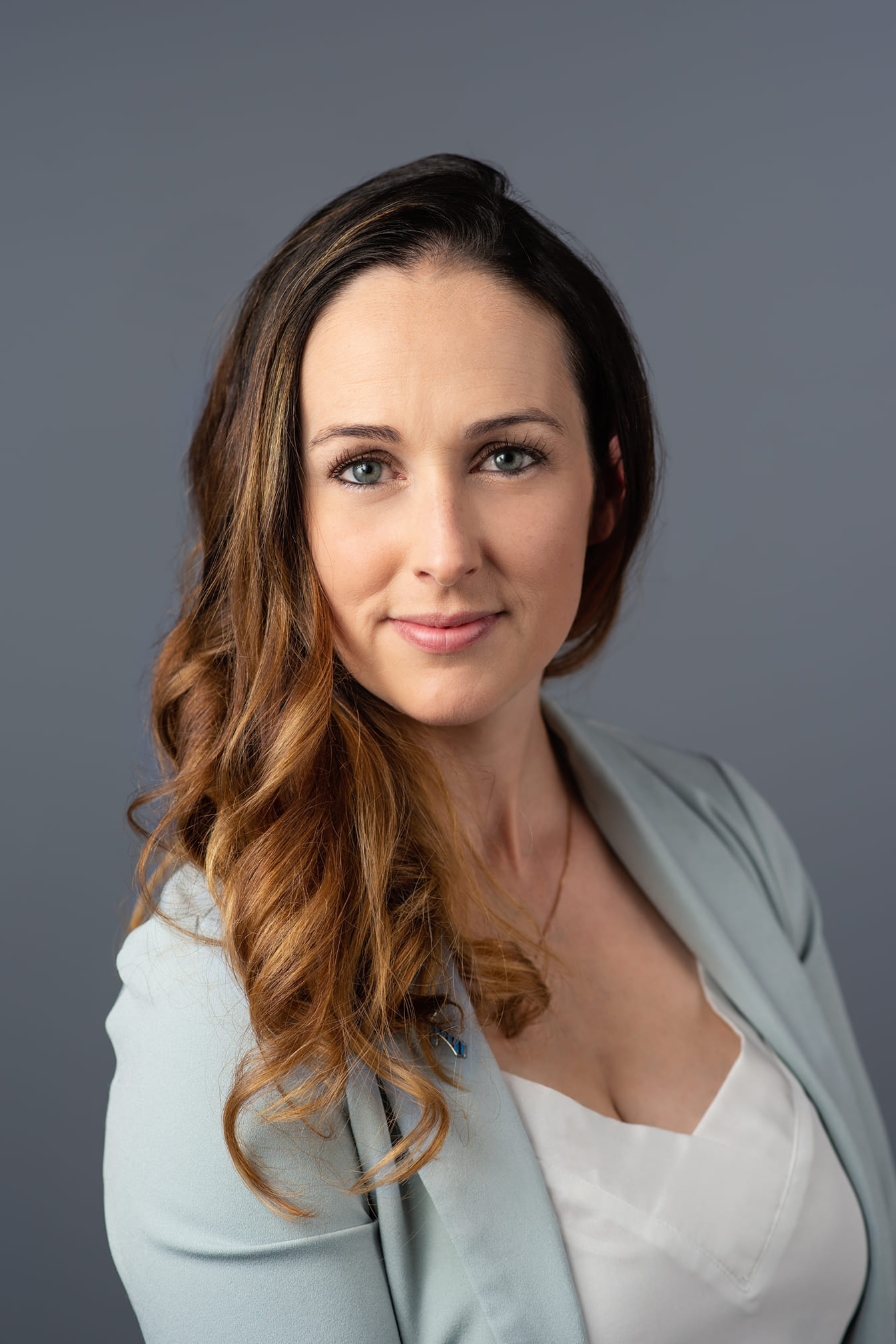 一个女人的头发，长长的棕色头发。她在白色上衣上穿着淡蓝色西装外套。