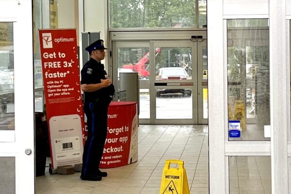 可以看到一家杂货店的入口，门口站着一名穿制服的警察。