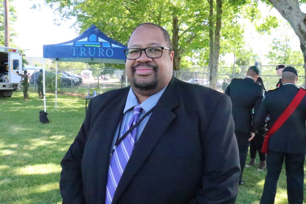 A Black man with glasses and a goatee in a dark suit.