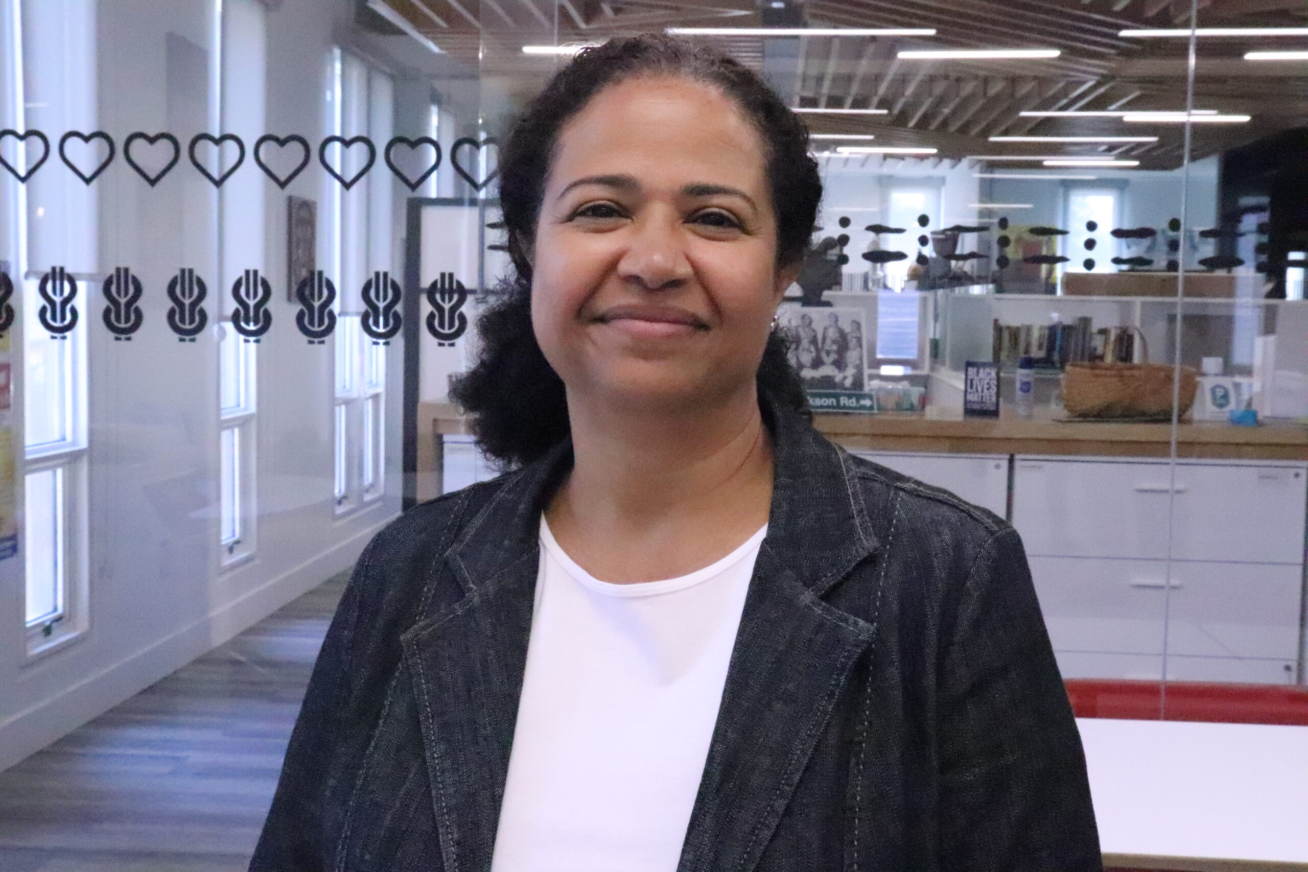 黑人妇女站在玻璃背景前微笑着照相机。