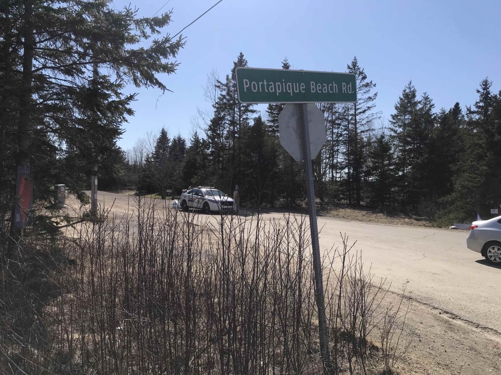 2020年4月25日，前景是Portapique海滩路的标志，一辆皇家骑警的汽车停在路上。照片:琼巴克斯特