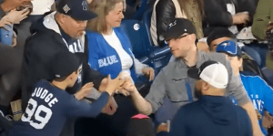 a man hands a baseball to a kid at a baseball game in the stands