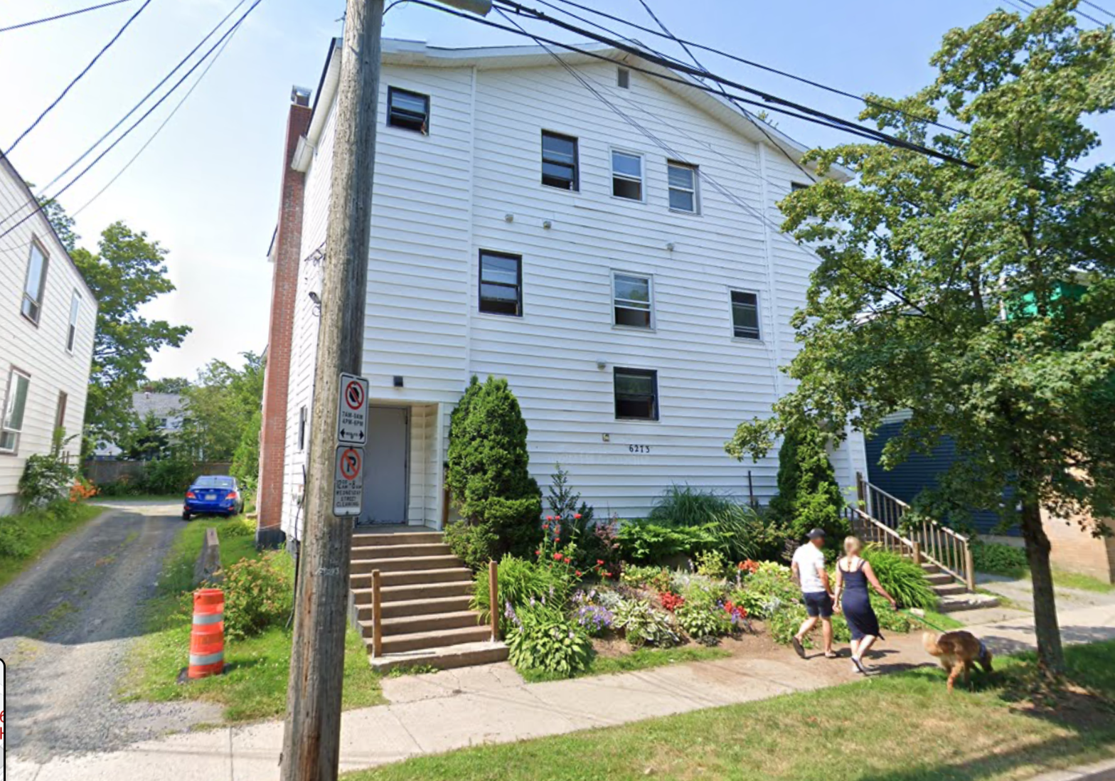 一幢白色的大房子，前面有两个人在遛狗