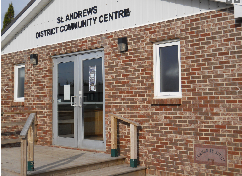 一座红砖建筑，有双前门、小窗户和楼梯。门上的牌子上写着圣安德鲁斯地区社区中心