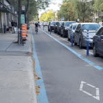 在一排停放的汽车和人行道之间的自行车道上骑车的人