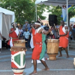 身穿橙色和绿色服装表演的非洲鼓手