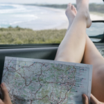 一位白人妇女在看地图时把腿搁在车窗上