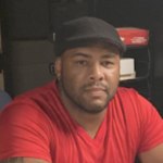 一个穿着红色t恤，戴着黑色棒球帽的黑人男子