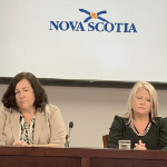 两个拿着麦克风的白人妇女坐在一张桌子旁，看起来相当失望