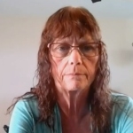 一个留着长发，戴着眼镜，穿着淡蓝绿色上衣的女人在Zoom会议上