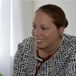 一位挽着头发、穿着黑白上衣的女医生正对着病人微笑。