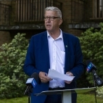 一名身穿蓝色西装的男子站在一间公寓前设立的讲台上