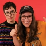 两个人站在一块橙色的屏幕前。