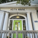 房子的正门，石灰绿色的门，白色的柱子和门廊。门上有个牌子写着维思府