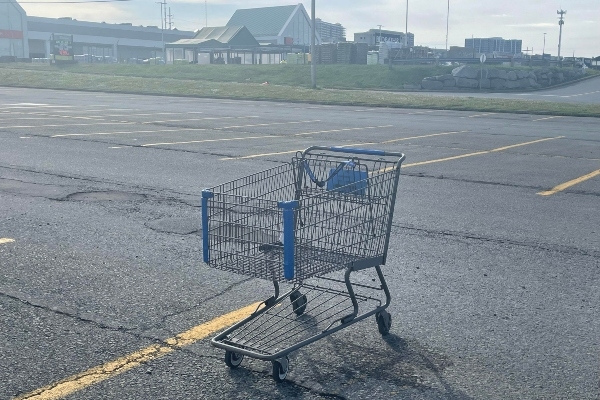 一辆购物车孤零零地停在空荡荡的停车场里。