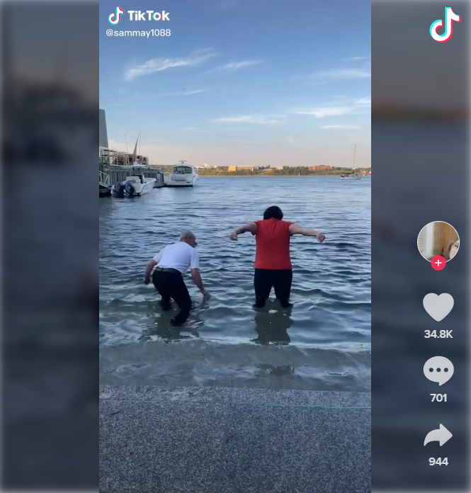 Two people jump into the water at the end of the stairs in the harbour