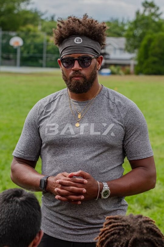 戴墨镜的黑人，灰色t恤，上面用白色写着