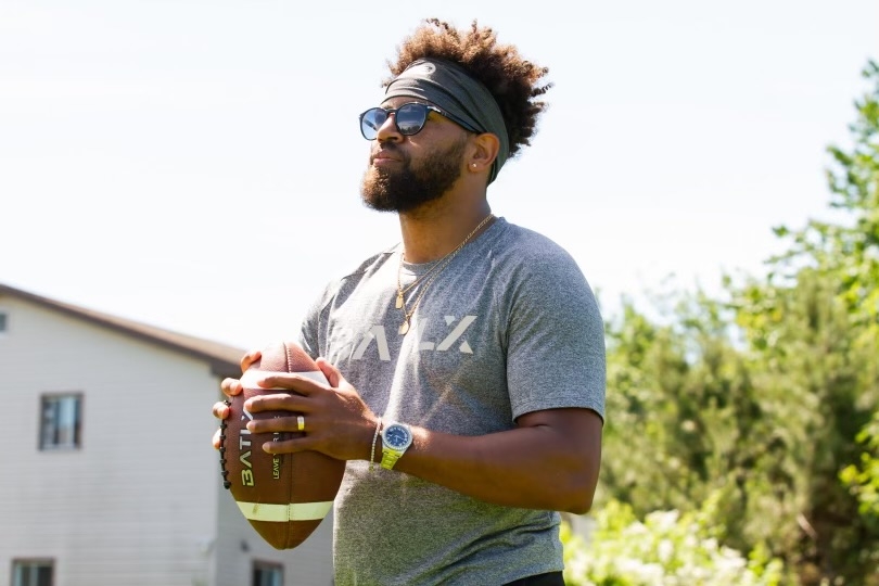 阳光照在一个戴着墨镜拿着足球的黑人身上