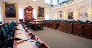 一个空房间，有蓝色的椅子，有麦克风的桌子，两幅画挂在一张大椅子旁边