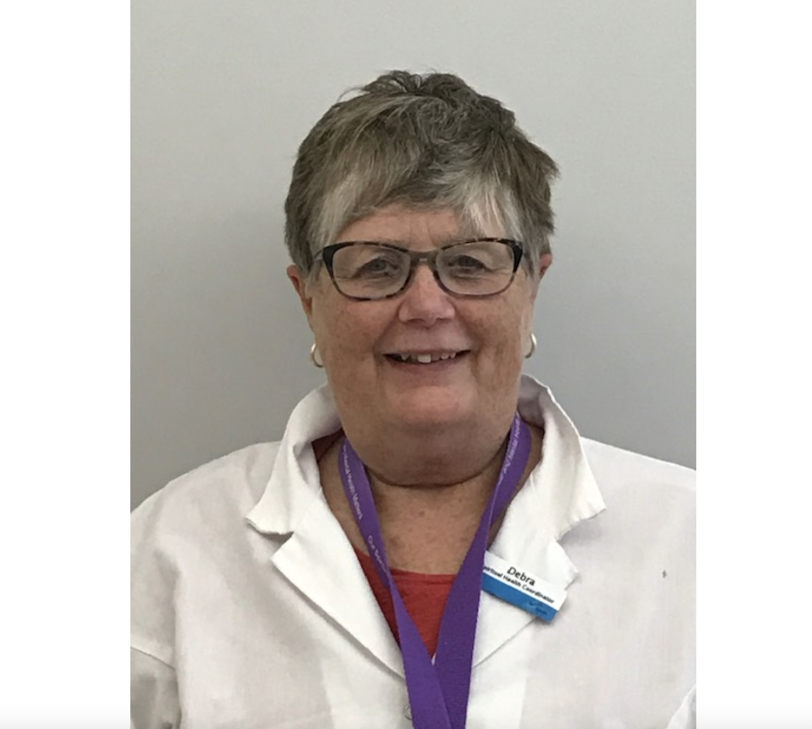 一个微笑的女人，穿着一件红色的衬衫，白色的外套，戴着眼镜