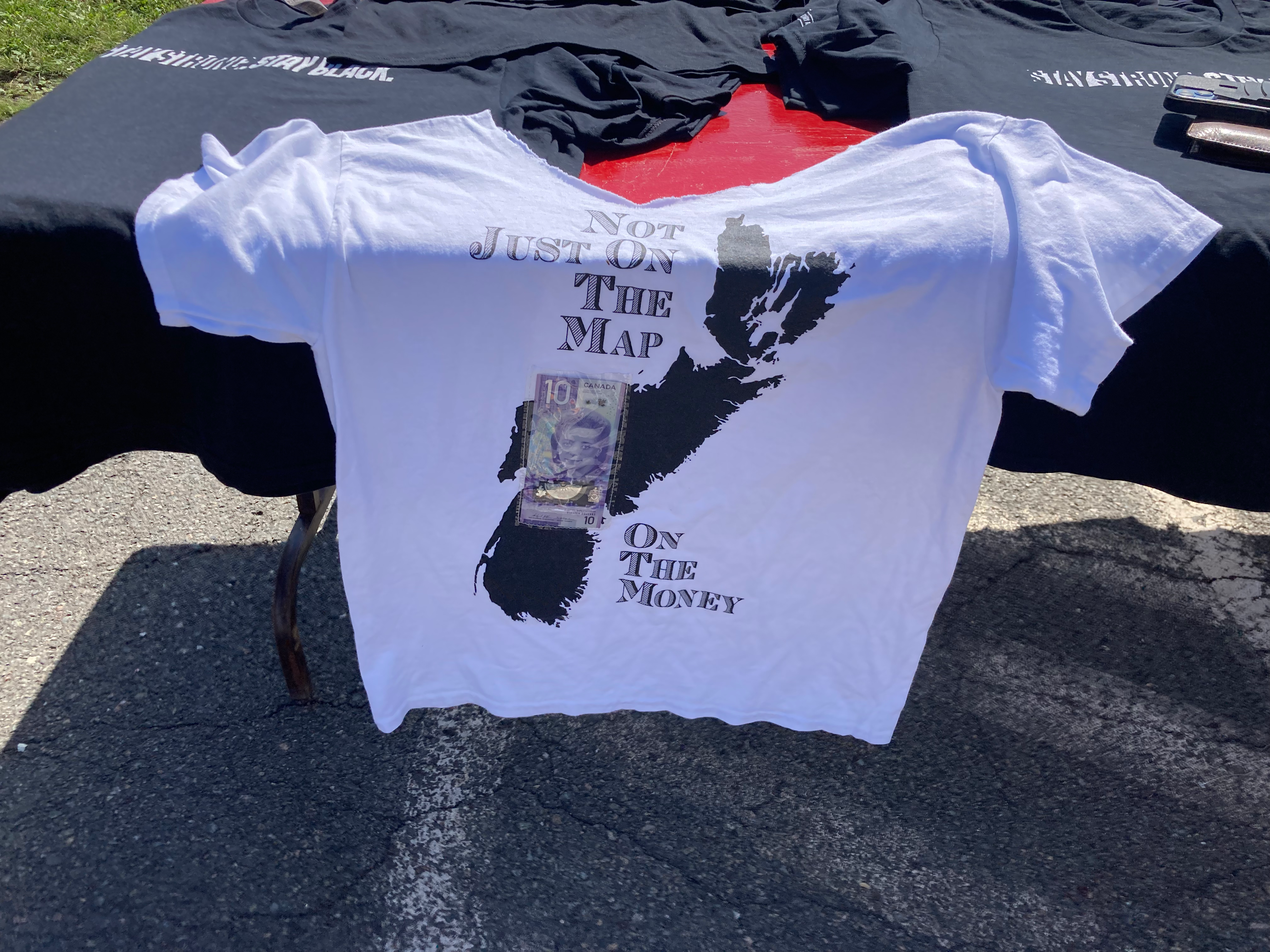 由塞德里克·斯迈利(Cedric Smiley)设计的印有新斯科舍省地图的t恤上，印有印有维奥拉·德斯蒙德(Viola Desmond) 10美元钞票的透明塑料嵌件