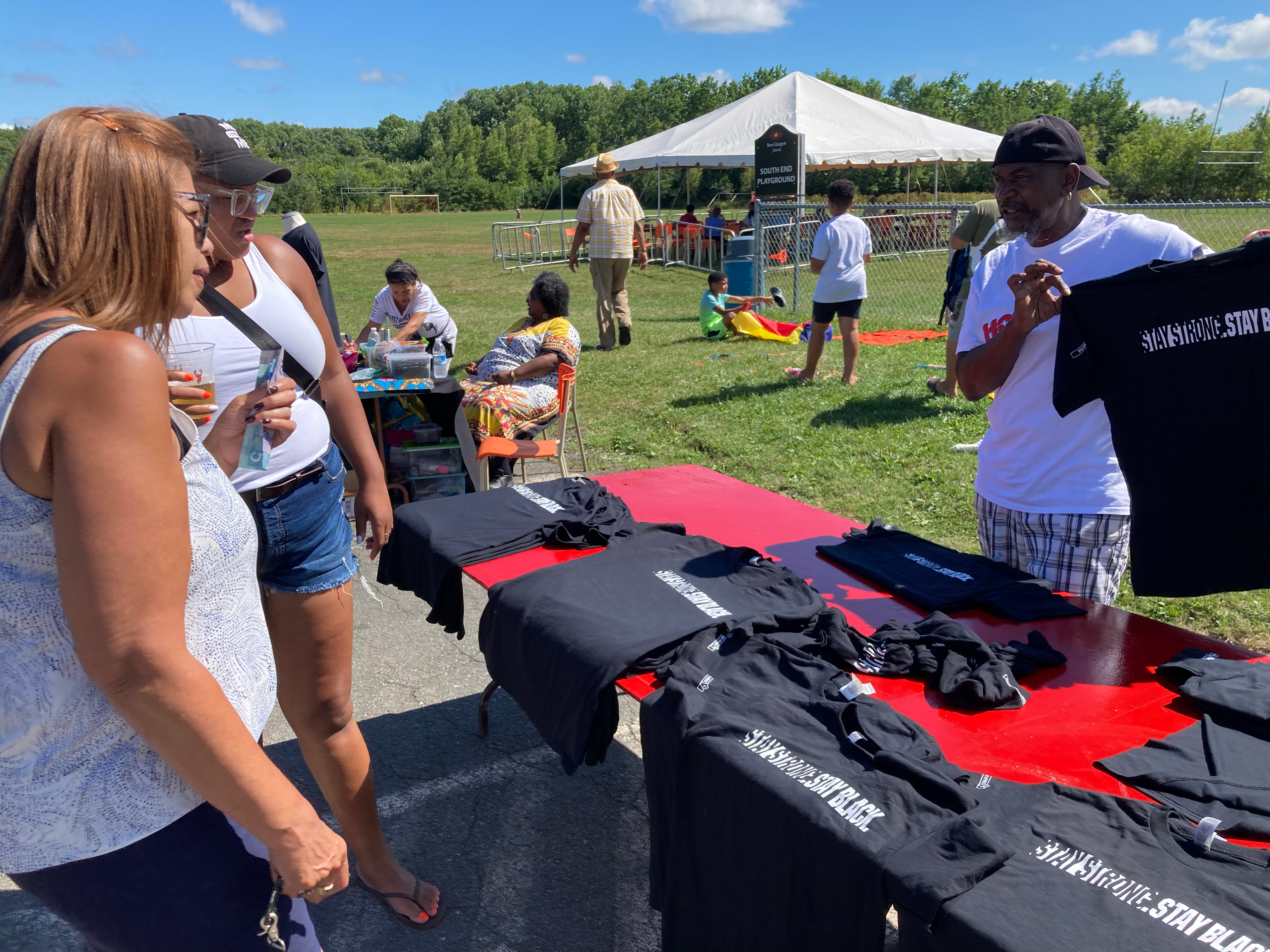 两个黑人看着一个黑人在卖《坚强》。保持黑色。的t恤