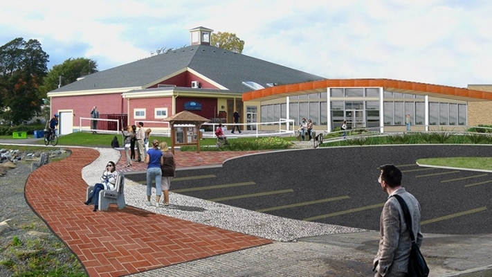 一个建筑效果图，前面有一个停车场，人们沿着一条小路走。