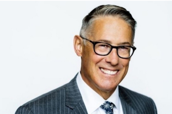 一个上了年纪的白种人，头发花白，戴着黑框眼镜，笑容灿烂