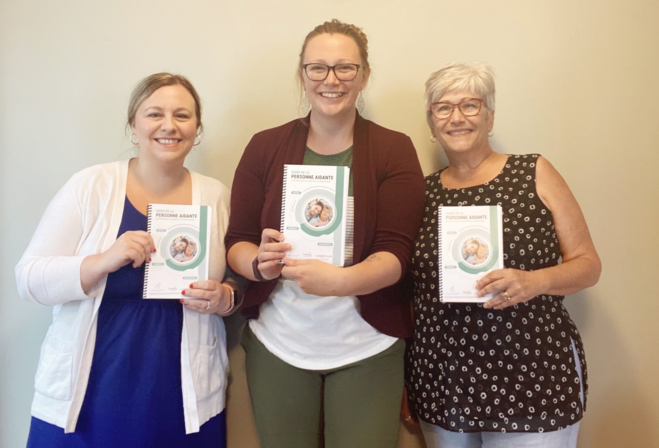 三个女人微笑着靠墙站着，手里拿着新推出的法语护理指南。