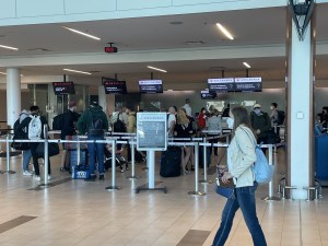 机场拥挤的行李托运处。数十人在用绳子围起来的队伍中等待前台接待员