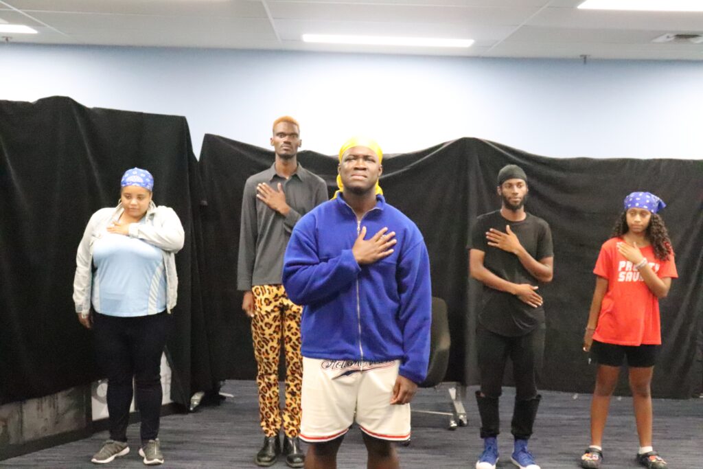 五名黑人演员用左手捂住心口排练一幕