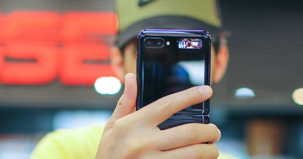 一个戴着棒球帽的年轻人把手机举在面前。