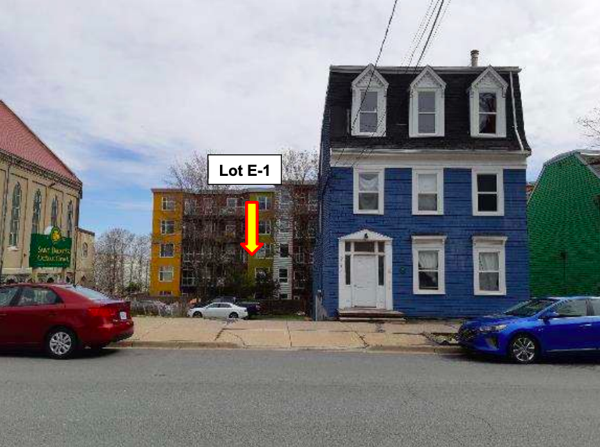 A blue house is seen on a grey day. To the left is a vacant property with an arrow denoting it's 