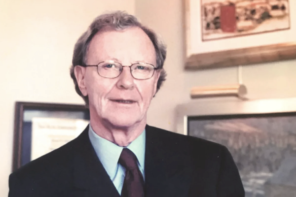 一个年长的女hite man with glasses standing in his office